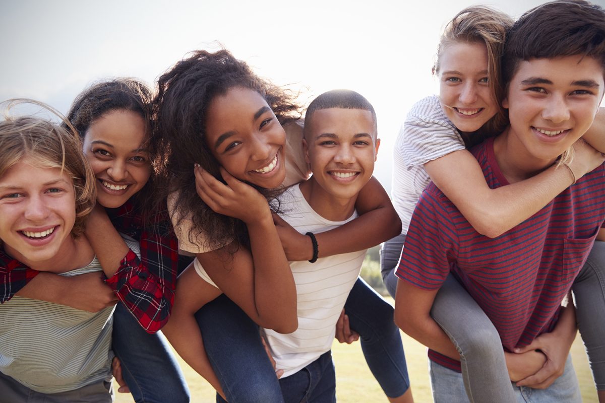 Teenage school friends having fun piggybacking outdoors Teenage school friends having fun piggybacking outdoors